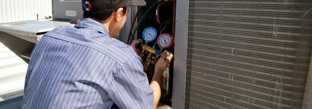 HVAC technician servicing a condenser unit in Ankeny